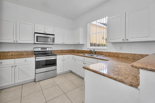 a kitchen with granite countertop white cabinets and white stainless steel appliances