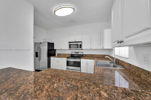 a kitchen with granite countertop a refrigerator sink and stove