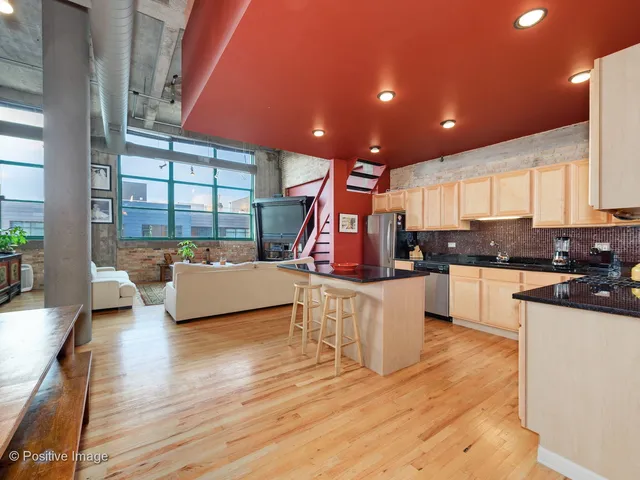 a kitchen with stainless steel appliances kitchen island granite countertop wooden floors and white cabinets