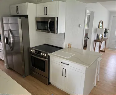 a kitchen with stainless steel appliances granite countertop a stove a refrigerator and a microwave