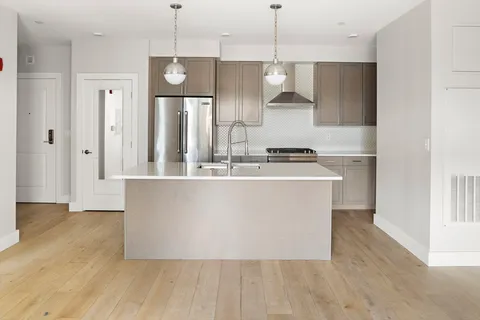 a view of a kitchen with stainless steel appliances granite countertop wooden floors and white walls