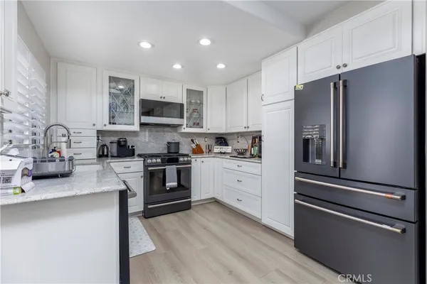a kitchen with granite countertop a refrigerator stove and sink
