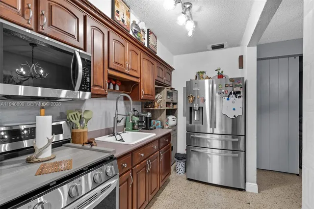 a kitchen with stainless steel appliances granite countertop a refrigerator a stove and a sink with dishwasher