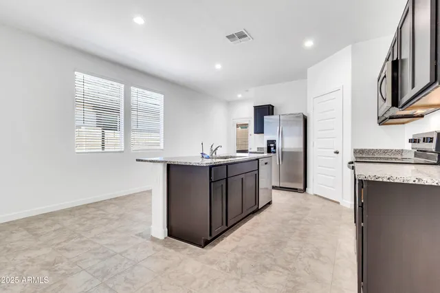 a kitchen with stainless steel appliances granite countertop a stove a sink a refrigerator and a microwave