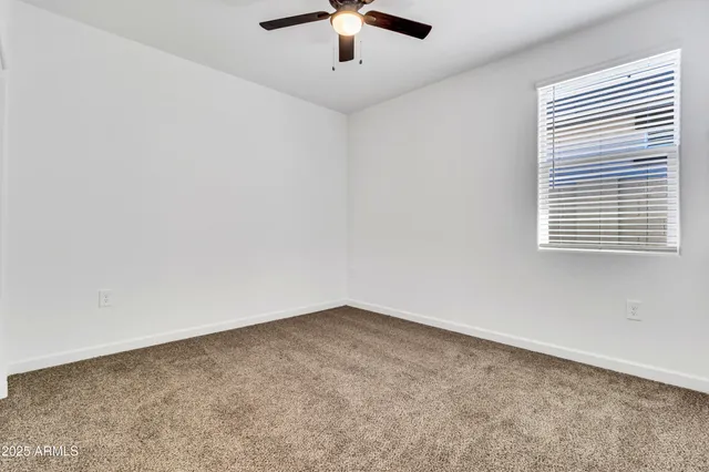 an empty room with a ceiling fan and window