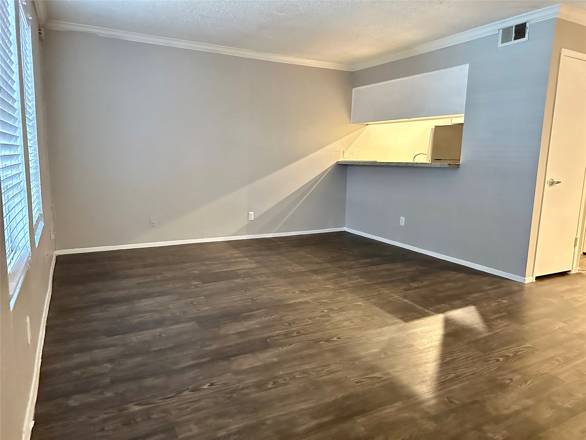 5426 Menchaca Road, Unit 119 Austin, TX 78745 - Photo 7 of 8 Spacious room featuring wood-finish flooring, light gray walls, and crown molding