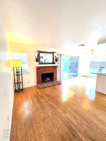 a view of empty room with a fireplace and wooden floor
