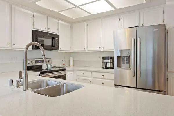 a kitchen with stainless steel appliances a refrigerator sink and white cabinets