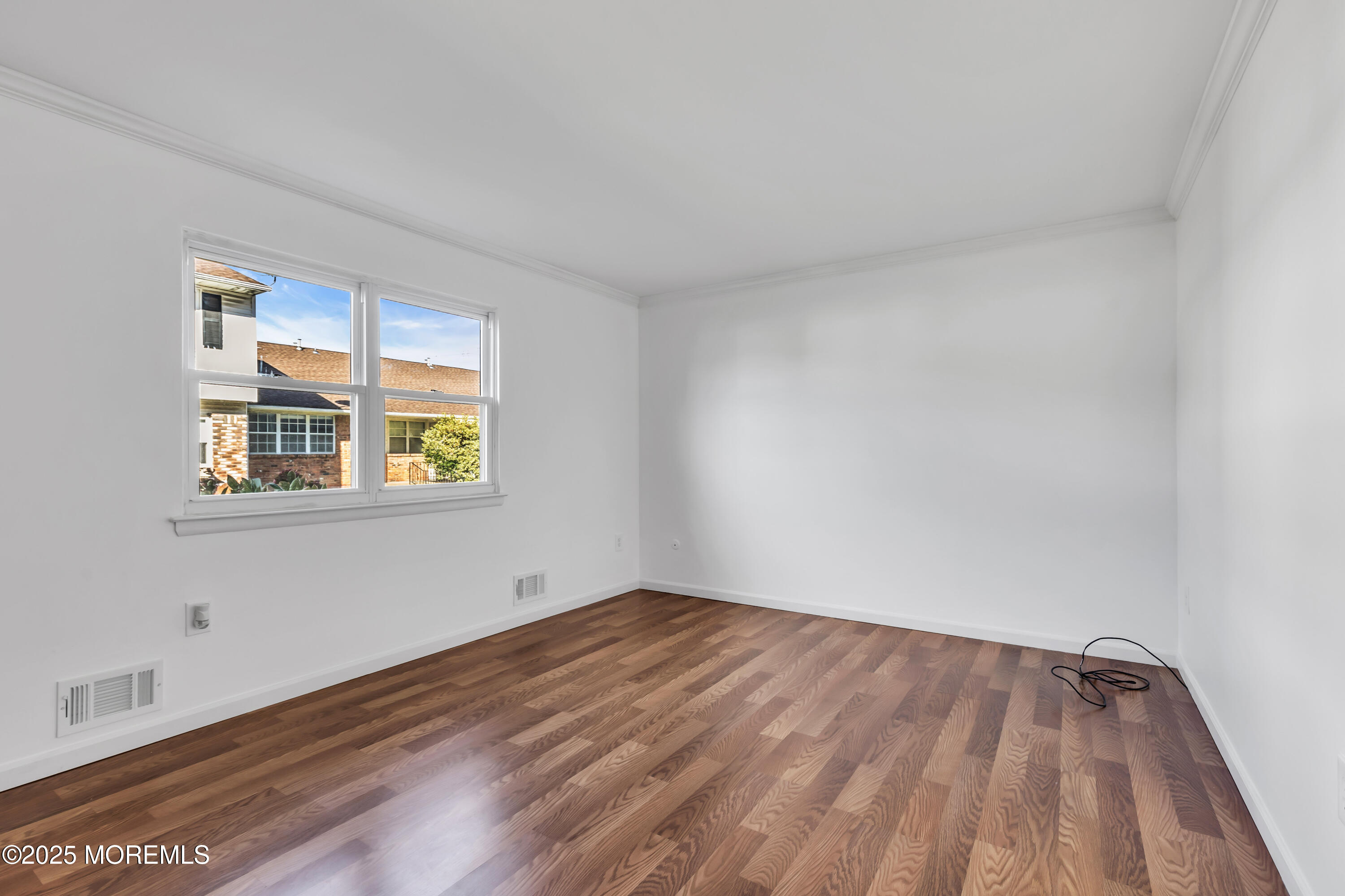 5 Indiana Court, Unit A Matawan, NJ 07747 - Photo 17 of 32 a view of an empty room with wooden floor and a window