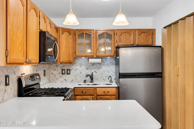a kitchen with stainless steel appliances granite countertop a refrigerator a stove and a sink
