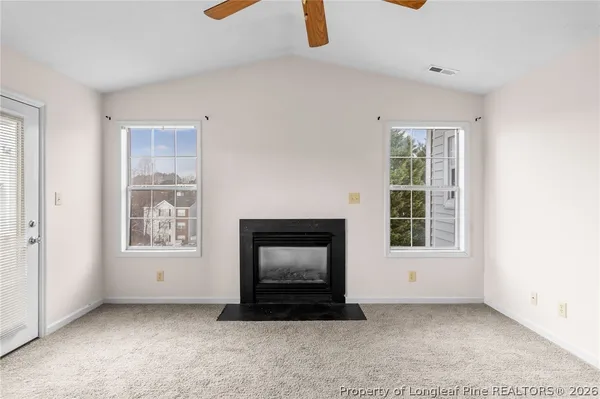 an empty room with windows and fireplace