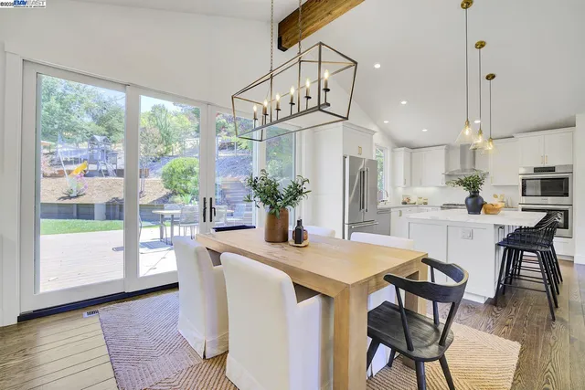 a kitchen with stainless steel appliances kitchen island granite countertop a table chairs in it and wooden floors