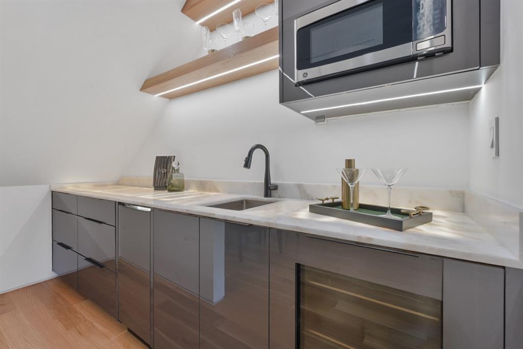 9457 Waterview Road Dallas, TX 75218 - Photo 21 of 25 Contemporary wet bar featuring a stainless steel sink, dark cabinetry, and light stone countertops