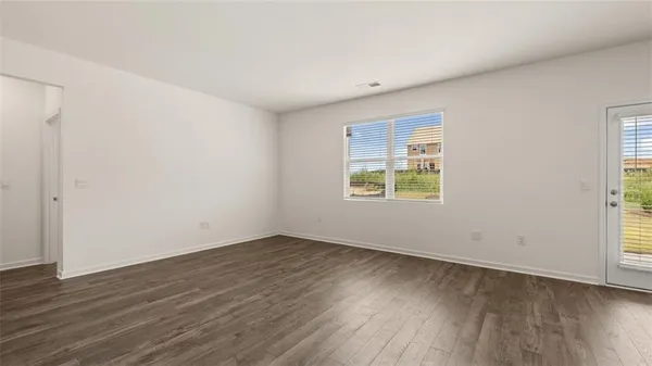 an empty room with wooden floor and windows