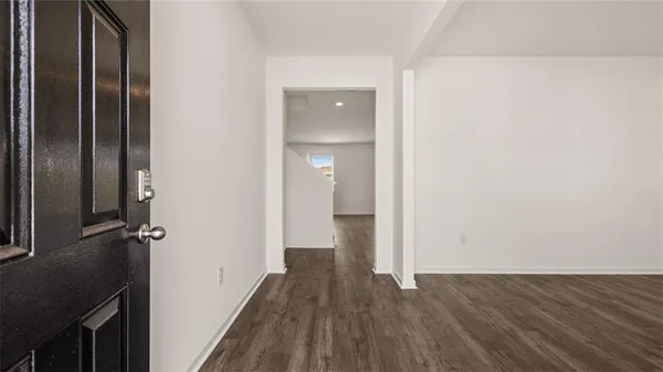 a view of a hallway with wooden floor and a bathroom
