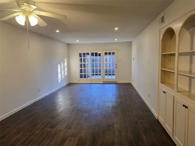a view of an empty room with window and wooden floor