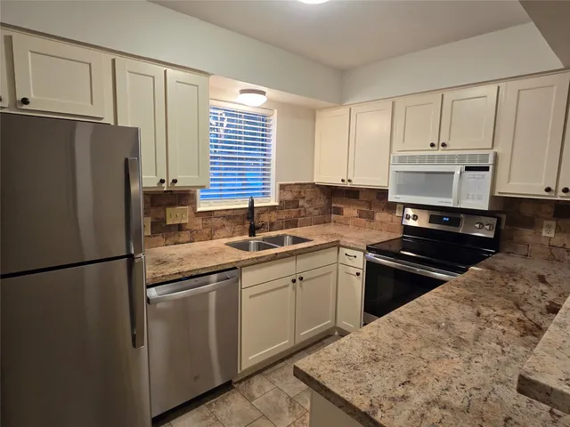 a kitchen with granite countertop white cabinets and stainless steel appliances