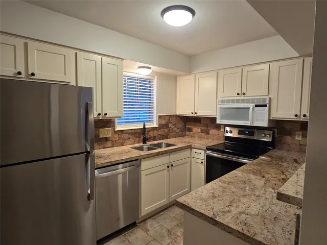 a kitchen with a sink a refrigerator and cabinets