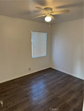 an empty room with wooden floor chandelier fan and window