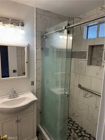 a bathroom with a sink shower and a mirror