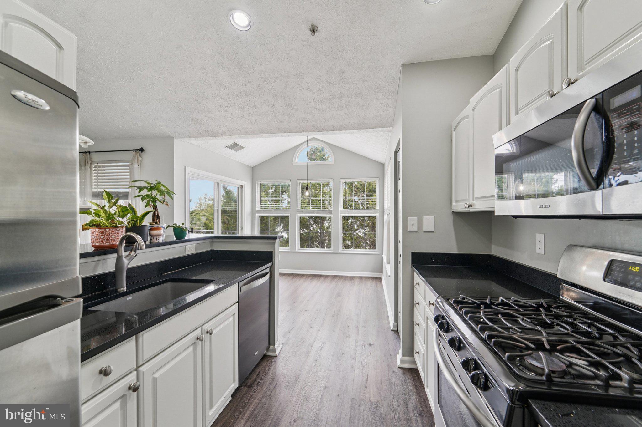 2444 Blue Spring Court, Unit 303 Odenton, MD 21113 - Photo 11 of 24 a kitchen with granite countertop a stove and cabinets