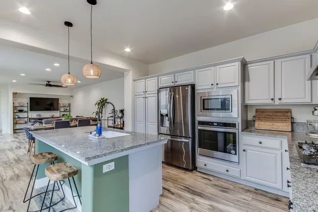 a kitchen with stainless steel appliances granite countertop a sink refrigerator and microwave