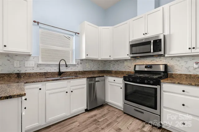 a kitchen with granite countertop white cabinets stainless steel appliances and a sink
