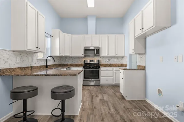 a kitchen with granite countertop a sink cabinets and stainless steel appliances