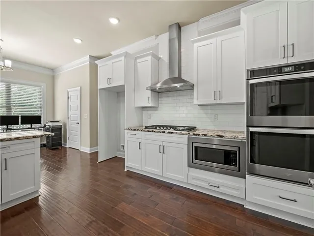 a kitchen with stainless steel appliances white cabinets and a stove top oven