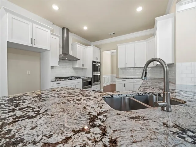 a kitchen with stainless steel appliances kitchen island a refrigerator sink and cabinets