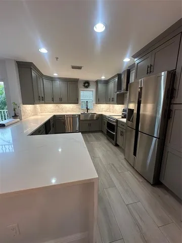 a kitchen with stainless steel appliances a refrigerator a sink a stove a microwave and a refrigerator