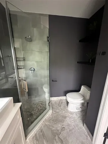 a bathroom with a granite countertop shower and a toilet