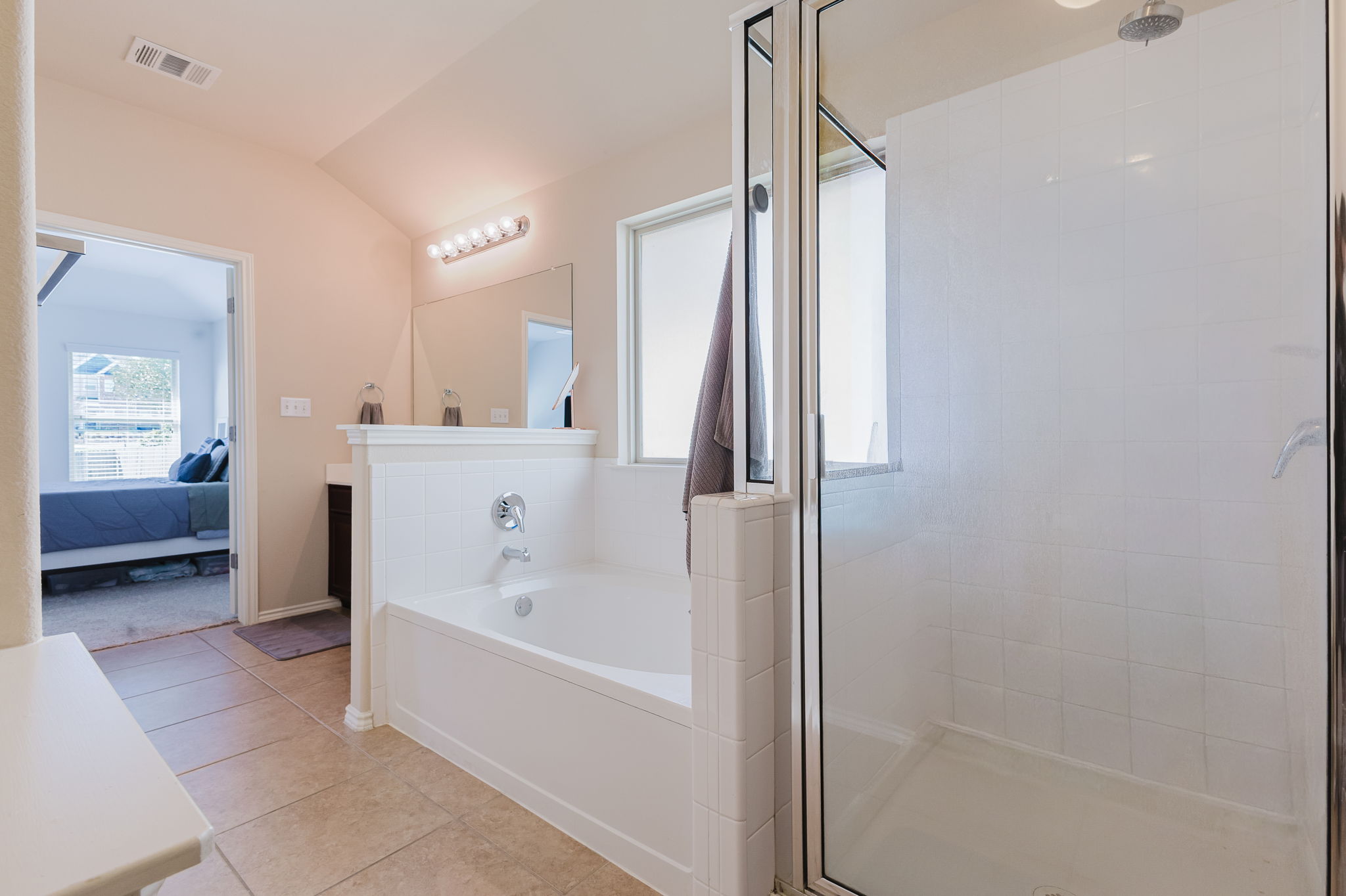 2292 Intrepid Drive Buda, TX 78610 - Photo 11 of 38 Ensuite bathroom with vanity, light tile patterned floors, a bath, a shower stall, and vaulted ceiling