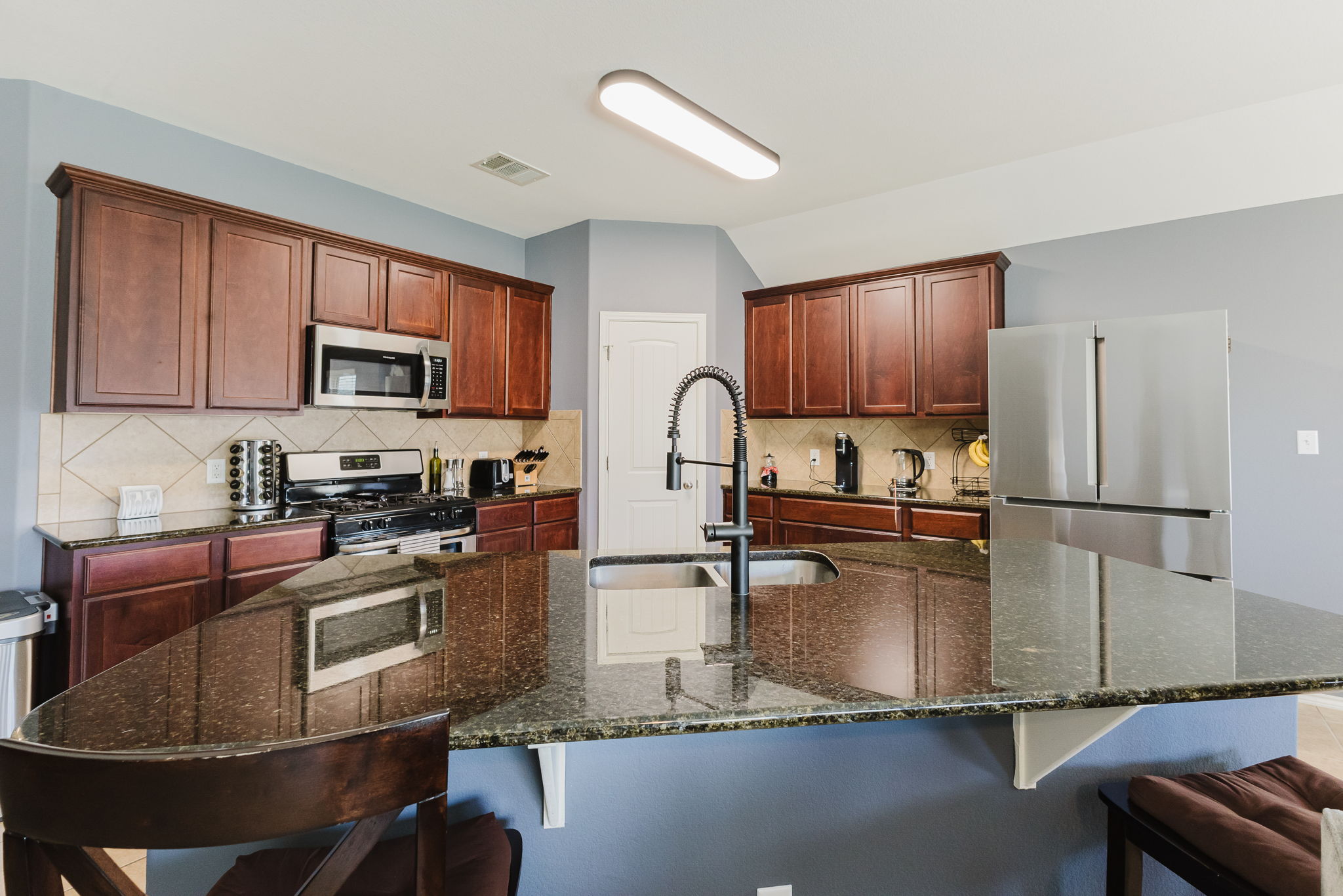 2292 Intrepid Drive Buda, TX 78610 - Photo 20 of 38 Kitchen with stainless steel appliances, a breakfast bar, dark stone counters, and a kitchen island with sink