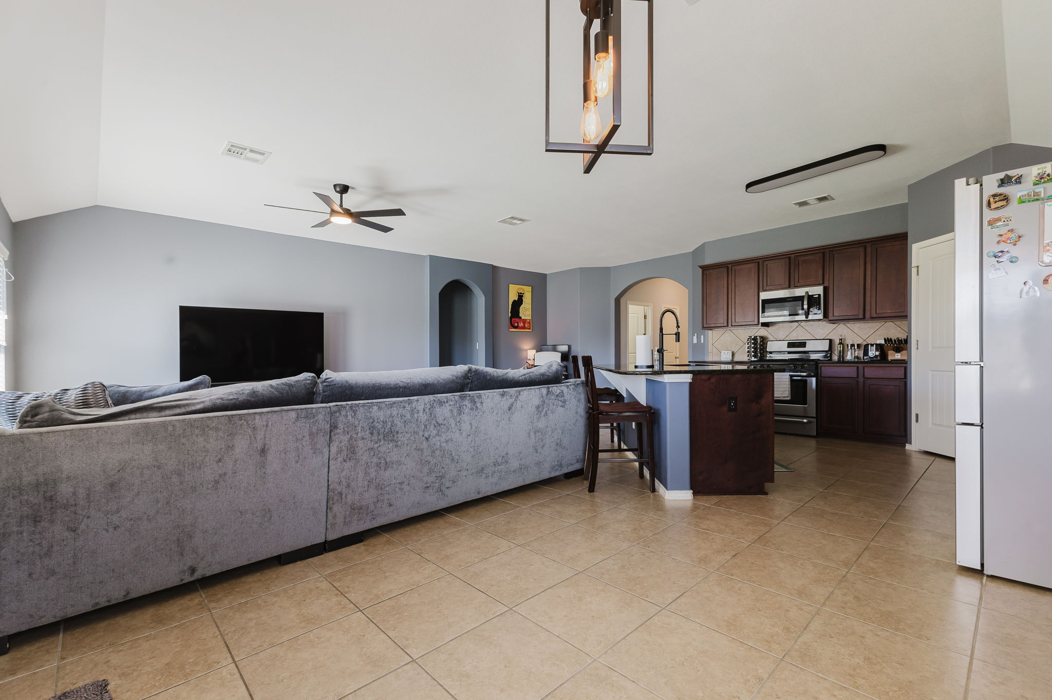 2292 Intrepid Drive Buda, TX 78610 - Photo 28 of 38 Living area featuring lofted ceiling, arched walkways, ceiling fan, and light tile patterned flooring