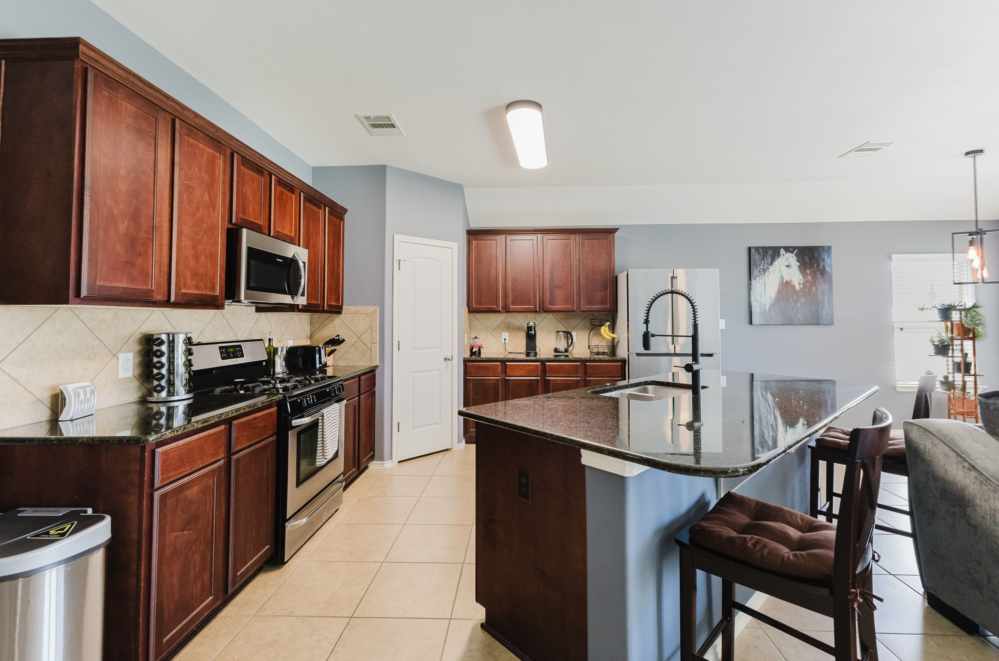 2292 Intrepid Drive Buda, TX 78610 - Photo 4 of 38 Kitchen with stainless steel appliances, dark stone counters, a kitchen bar, a kitchen island with sink, and light tile patterned flooring