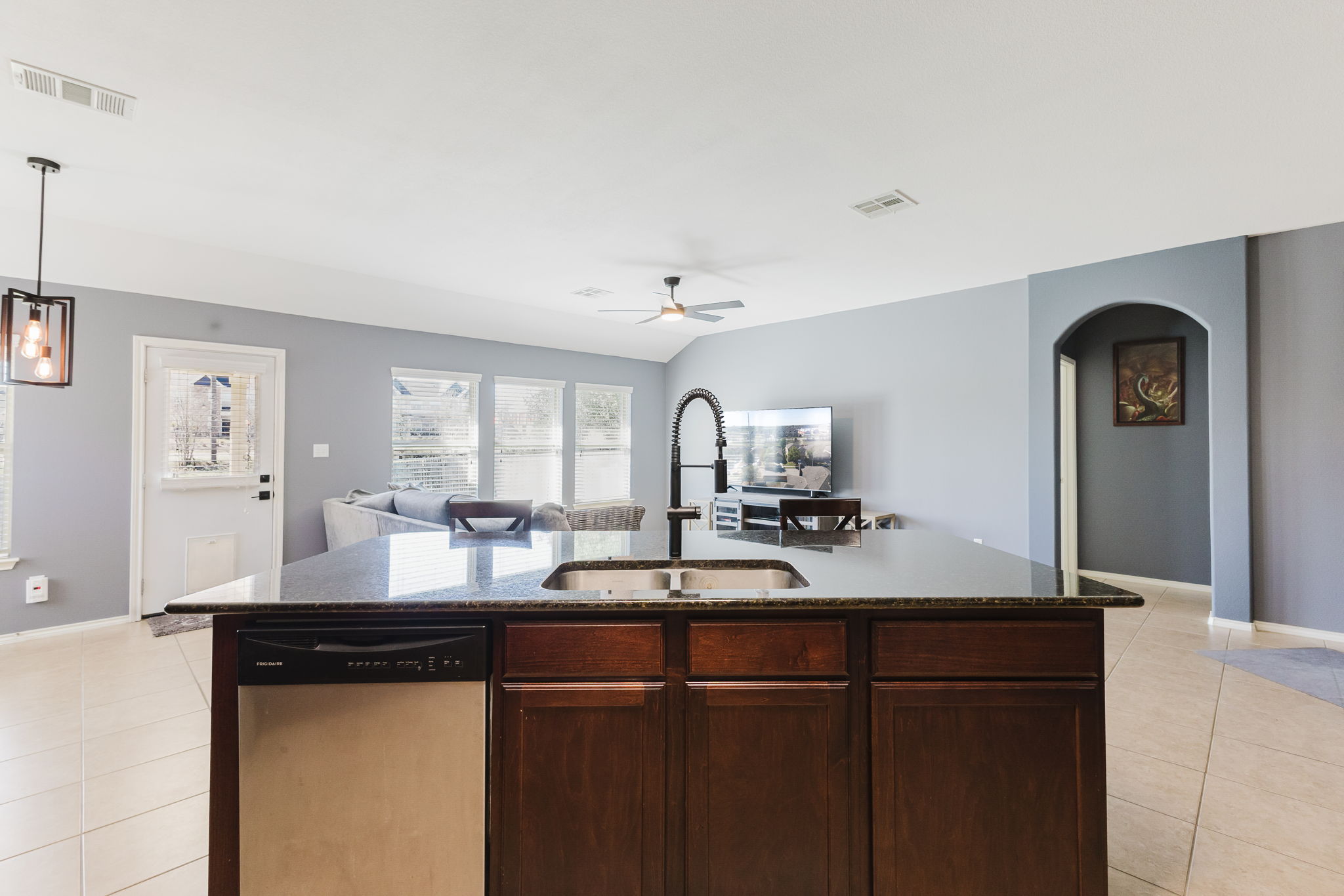 2292 Intrepid Drive Buda, TX 78610 - Photo 38 of 38 Kitchen featuring open floor plan, stainless steel dishwasher, light tile patterned floors, and arched walkways