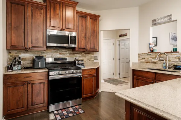 a kitchen with stainless steel appliances granite countertop wooden cabinets sink and stove top oven