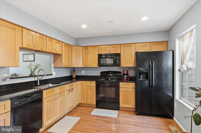 a kitchen with granite countertop a refrigerator a sink a stove and cabinets