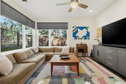 a living room with furniture a flat screen tv and a floor to ceiling window