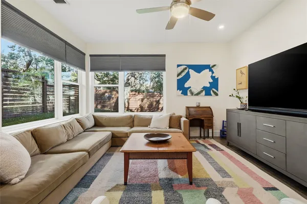 a living room with furniture a flat screen tv and a floor to ceiling window
