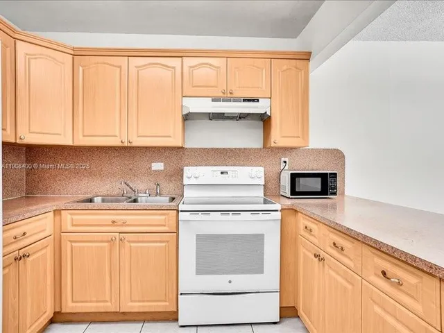 a kitchen with granite countertop white cabinets and white appliances