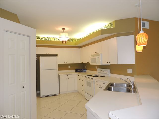 23891 Costa Del Sol Road, Unit 103 Bonita Springs, FL 34135 - Photo 2 of 12 a kitchen that has a sink cabinets and a refrigerator