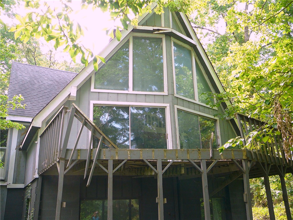 Perched among verdant trees, this unique A-frame structure offers elevated deck access and a wall of windows.