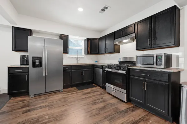 a kitchen with granite countertop a refrigerator stove and microwave