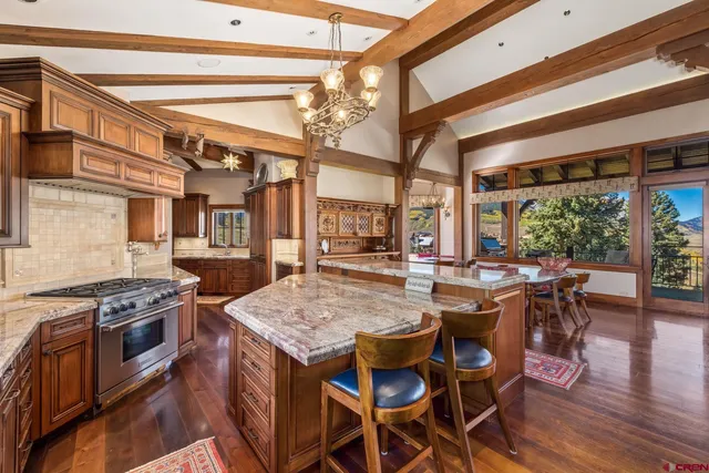 a open kitchen with stainless steel appliances granite countertop a stove top oven a dining table and chairs with wooden floor