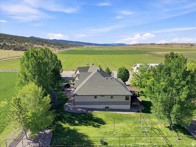 11290 South Southfield Road Mayfield, UT 84643 - Photo 11 of 103 Property featuring a multi-level structure with a gabled roof and covered patio, surrounded by mature trees and manicured lawns, with distant mountains and fields