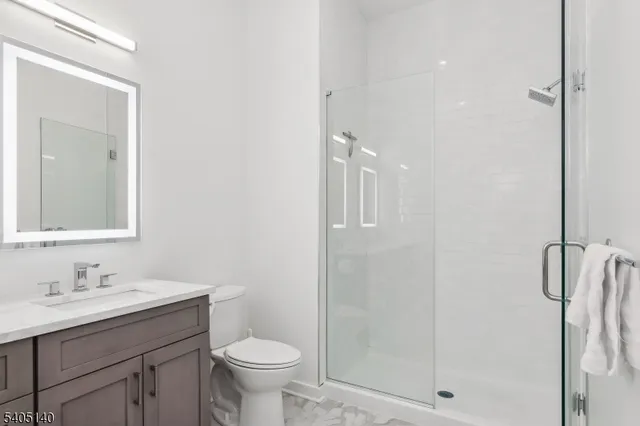 a bathroom with a shower sink vanity and toilet