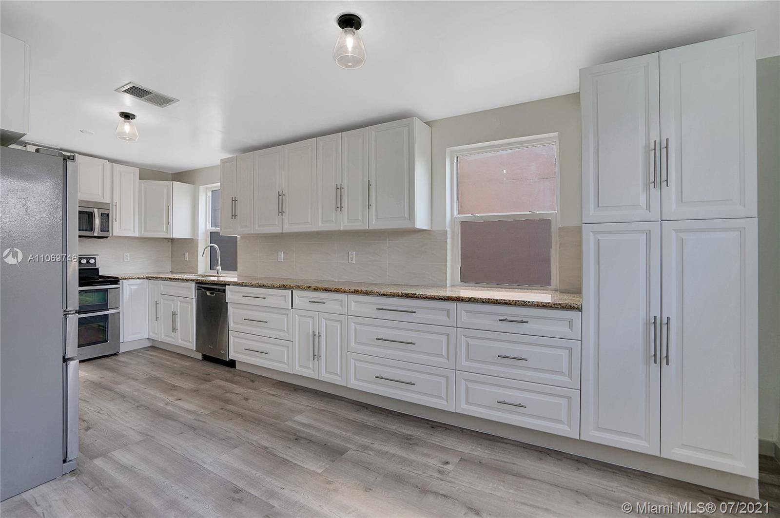 a kitchen with granite countertop white cabinets and stainless steel appliances