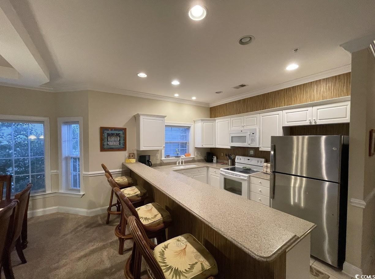1008 Ray Costin Way, Unit 310 Murrells Inlet, SC 29576 - Photo 12 of 40 Kitchen with dark colored carpet, white cabinets, kitchen peninsula, a kitchen breakfast bar, and white appliances